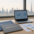 Office desk with two HR certification folders, laptop with blurred analytics, Gulf skyline backdrop — CIPD vs SHRM UAE